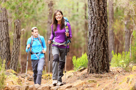 Two people hiking in the woods. Prevent foot pain, ankle pain and blisters on feet with proper fitting shoes. 