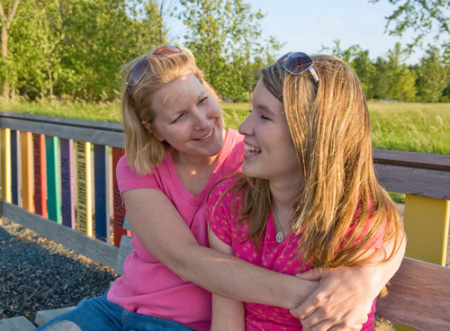 mother hugging daughter in a park
