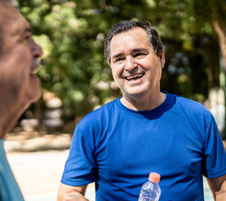 Middle-aged man in blue shirt standing outside talking about the early signs of heart disease for males