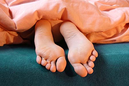 Growing pains, Teenager's feet sticking out of bed covers 