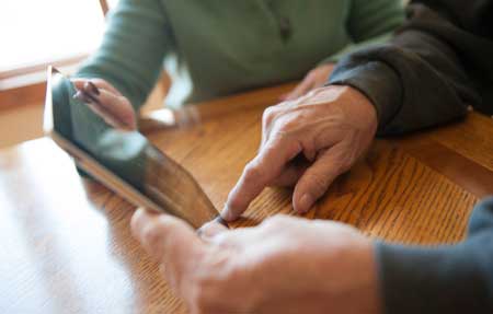 Older male and companion looking at a touch screen device
