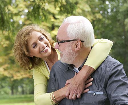Woman hugging man around neck from behind