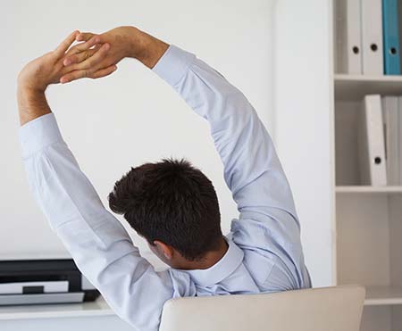 Man stretching his arms and neck at office desk