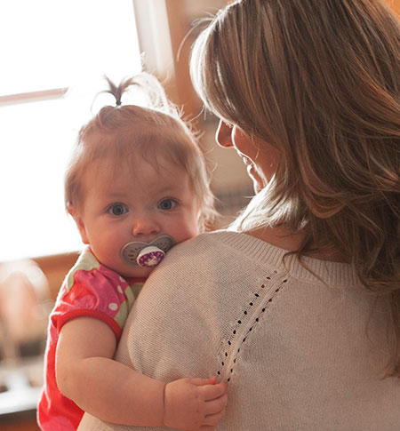 Mom holding cute baby girl with a pacifier