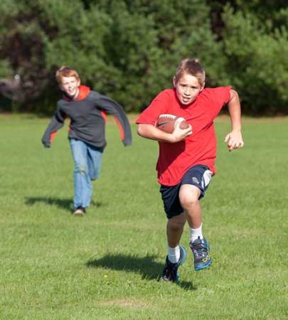 boy with signs of concussion running with a football outside