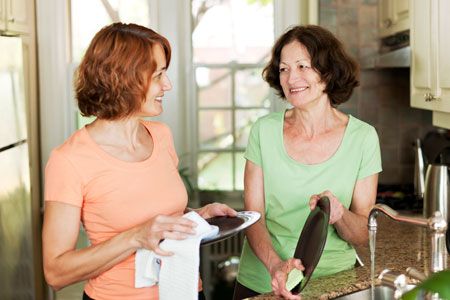 Two women wash dishes and talking