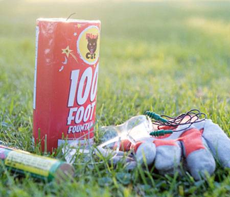 protective gloves and goggles next to fireworks to show safety tips
