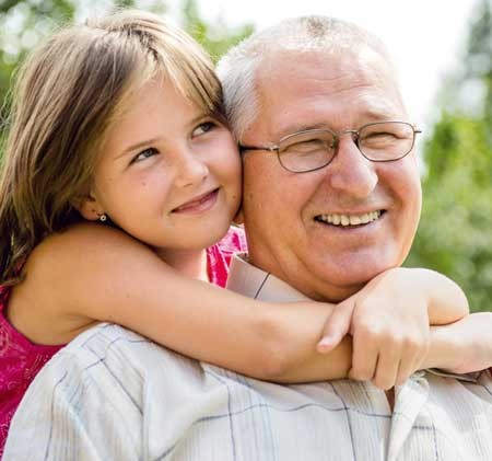 Young girl hugging grandpa around his neck