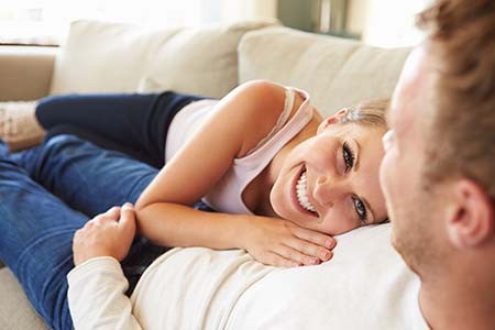 Younger couple laying on the couch together