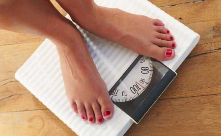 Women's feet on scale concerned about eating disorders