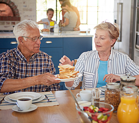 Senior man and senior woman having breakfast, passing a plate stacked with toast - Diabetes and your bones