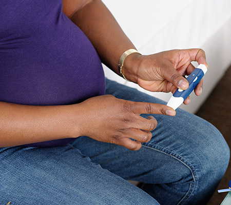 Pregnant woman testing her blood sugar - Gestational diabetes
