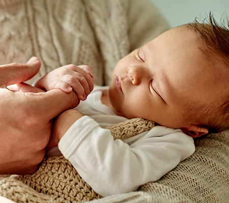 Mother holding a sleeping baby's hand in her arms - Non-verbal signs and symptoms