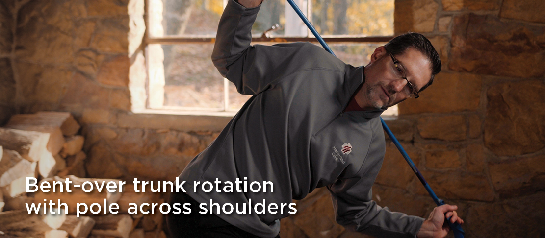 bent-over trunk rotation with ski pole across shoulders warmup before skiing