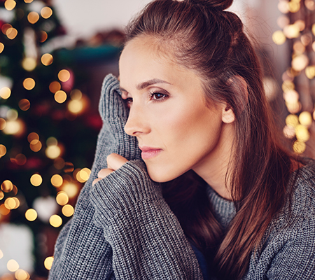 A sad woman in a Christmas scene - Helping loved ones with illness during holidays