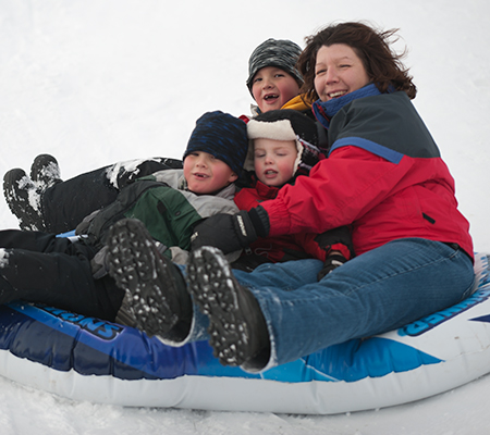 Family concerned about asthma in cold weather sliding down a hill on an inner tube 