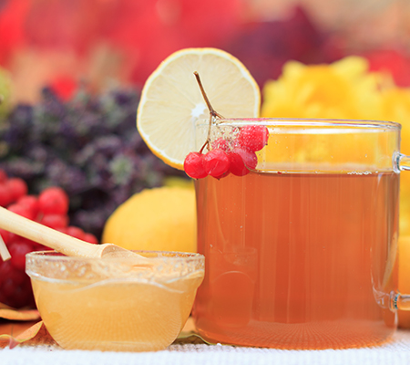 Mug of tea with lots of fruit in the background - Kombucha