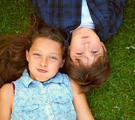 Two young kids holding their breath and laying on the lawn - Breath-holding spells