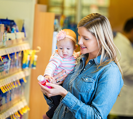 Mother and baby at the pharmacy looking at a medicine bottle - Vitamin D for breastfed infants