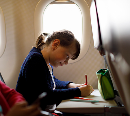 Girl drawing on a plane as distraction - Flying with kids