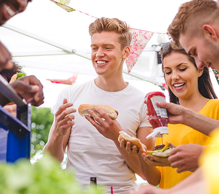 Man eating a hot dog at a cookout with a group of friends - What to do after binge eating