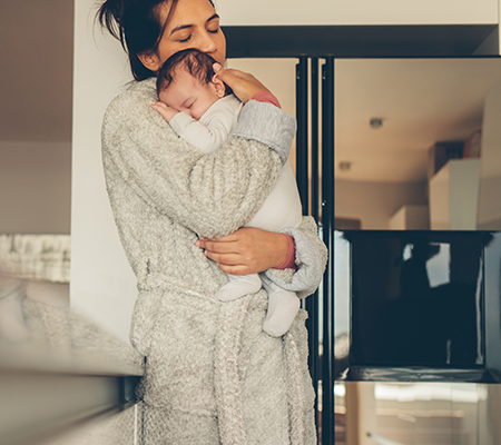 Mother holding baby in the kitchen - Breastfeeding while sick