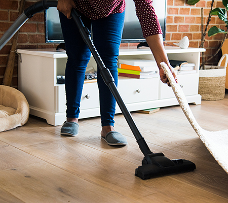 Woman vacuuming under a rug - Benefits of tidying up
