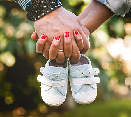 man and woman holding hands with baby shoes / how to deal with miscarriages and childhood death