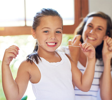 Photo of young girl flossing her teeth