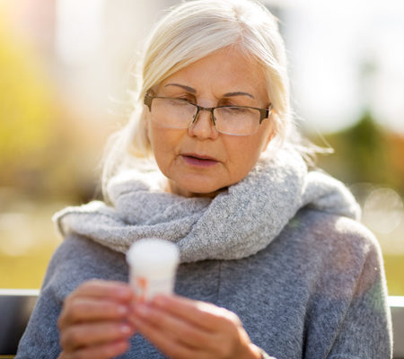 woman reading pill bottle in a park wondering if she has any signs of opioid addiction