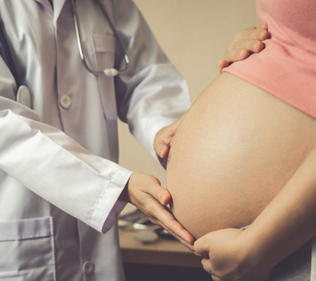Photo of a physician checking a pregnant woman's stomach