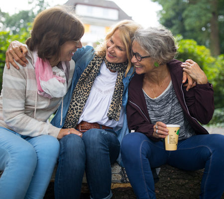 three women sitting down laughing about perimenopause symptoms