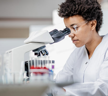 lab employee looking through a microscope