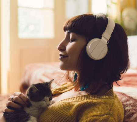 A woman relaxes while petting a cat.