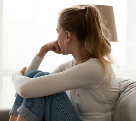 A stressed woman looks out a window.