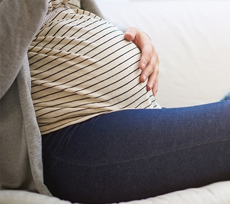 A pregnant woman sits on a couch considering c-section