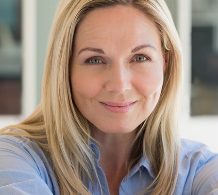 Portrait of happy woman in blue shirt smiling concerned about vaginal dryness and itching