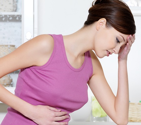 Pregnant woman with strong pain of stomach and nausea sitting in bathroom