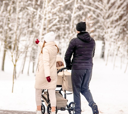 A married couple rolls a child in a wheelchair in the winter Park 
