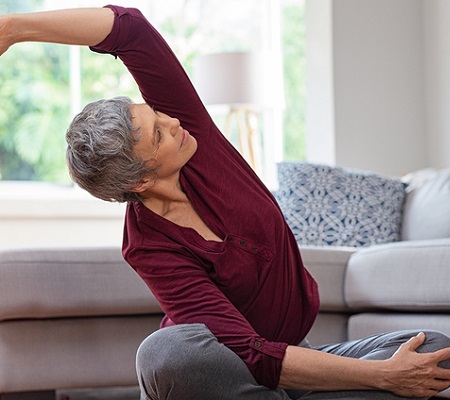 Senior woman exercising while sitting in lotus position.