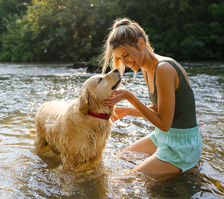 adult playing with dog in lake could cause summer skin problems