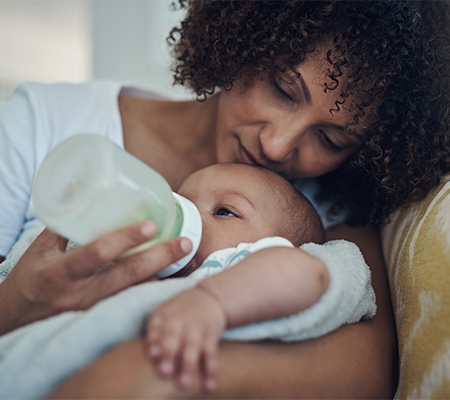 woman kissing baby as she feeds them