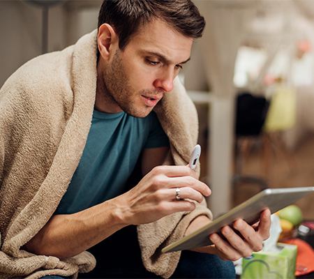 man holding thermometer and tablet looking up mpox symptoms