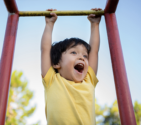 Child hanging from monkey bars while parents explore pediatric spine concerns