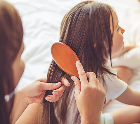Parent brushing lice out of child's hair, treat lice at home