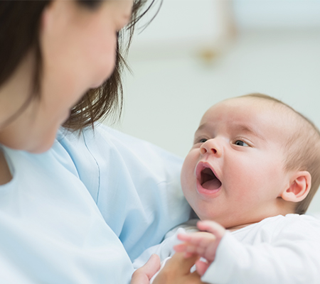 A newborn baby being held and looking up at their mother.