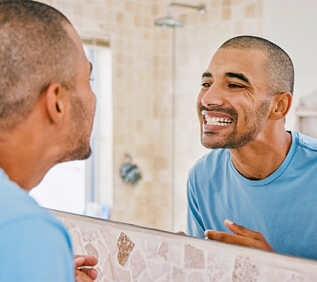 man looking at teeth considering using oil pulling, charcoal toothpaste and teeth bleaching