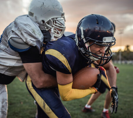 Two football players wearing sports safety gear. 