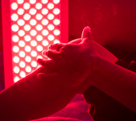 A person's bent leg with hand on it for red light therapy 