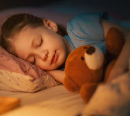 A photo of a little girl sleeping with her teddy bear getting the correct sleeping hours for kids 